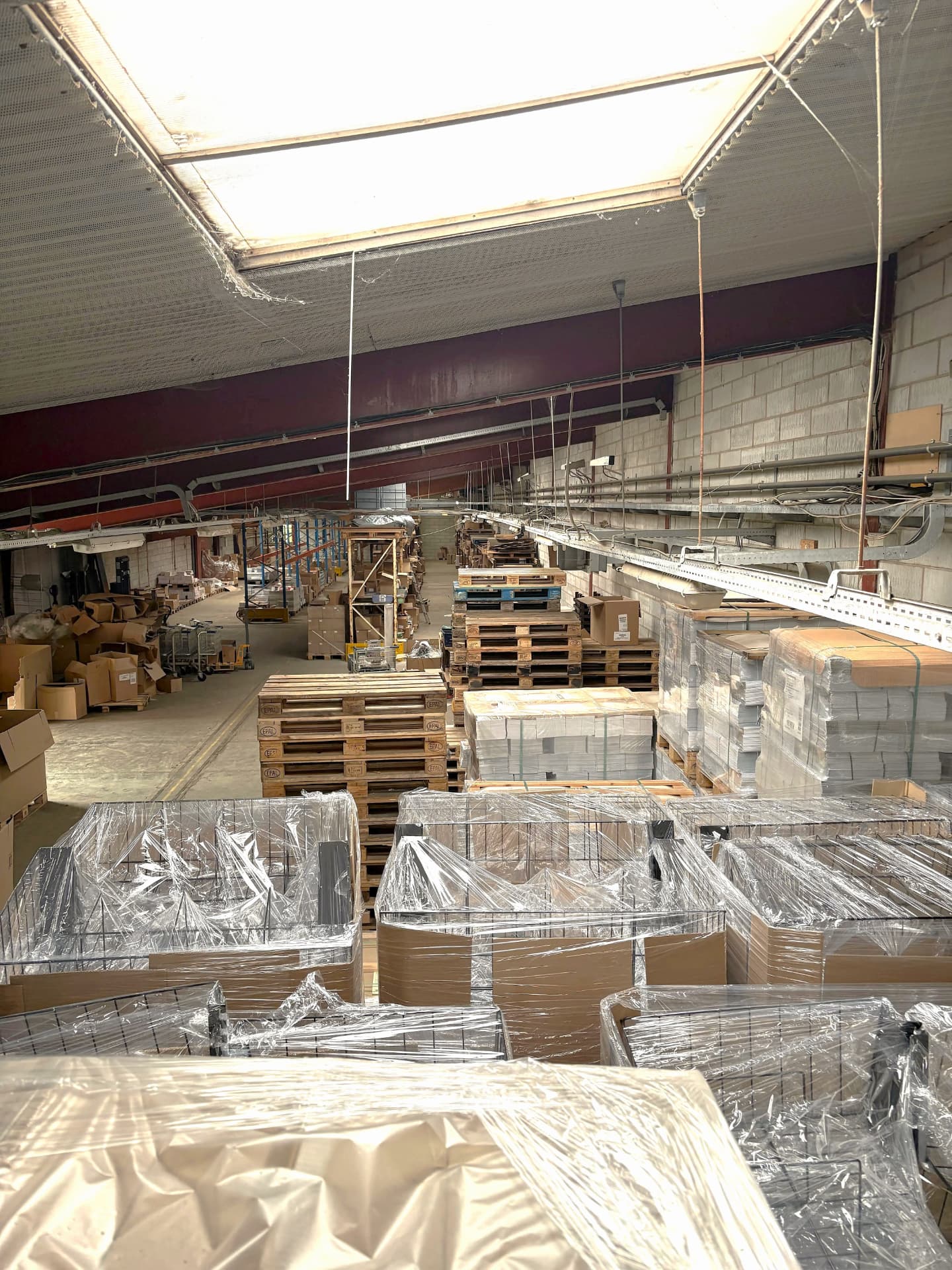 Neatly stacked pallets of printed brochures in a bright distribution warehouse
